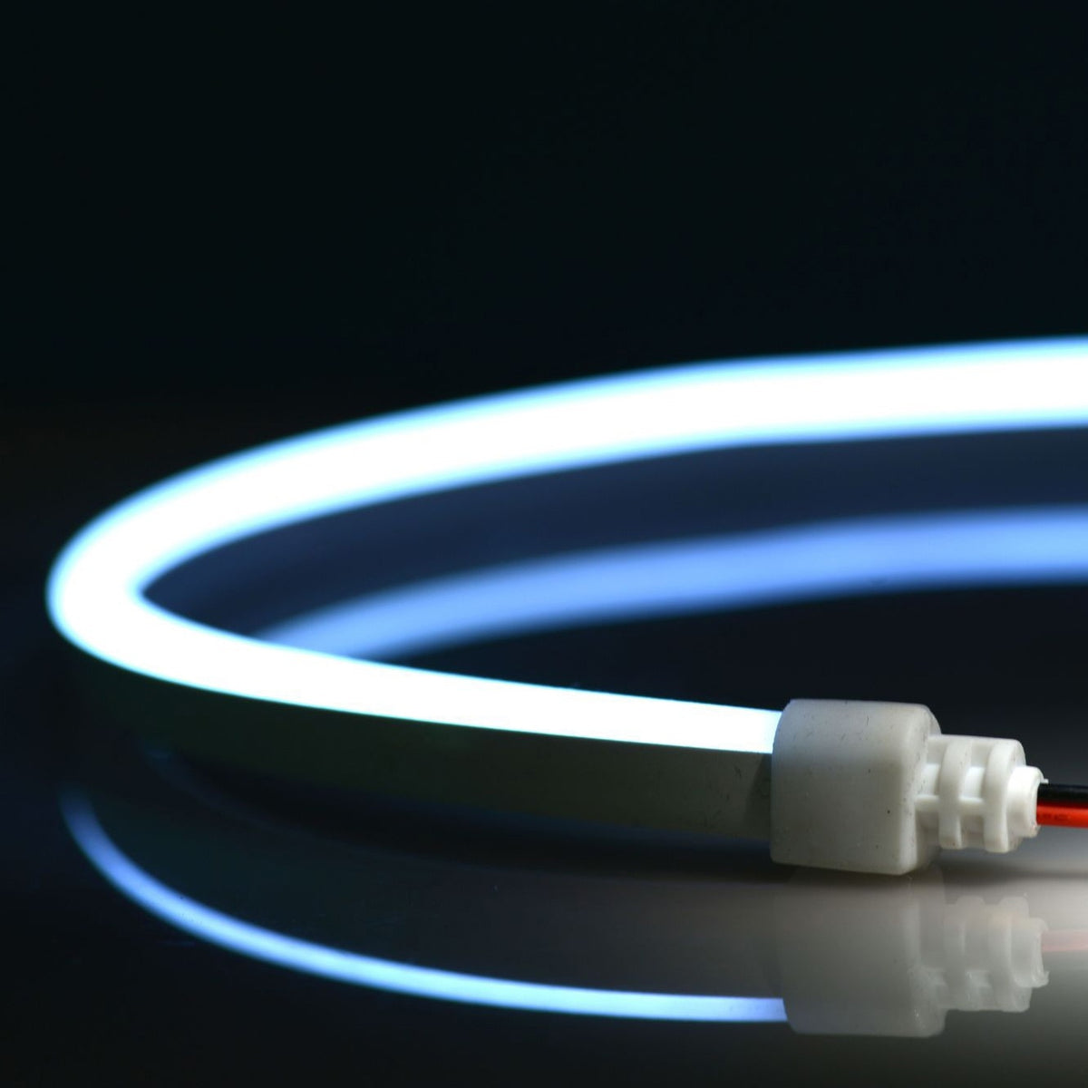 QolorFLEX NuNeon N914-CW-10 cool white LED neon tape illuminated and coiled, showing white end cap with two-wire lead, City Theatrical