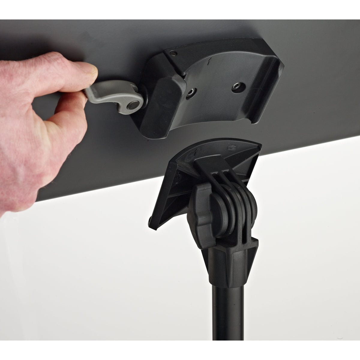11960 music stand quick-release desk mount detail with hand operating grey release lever above tilt bracket and black tightening knob, K&M