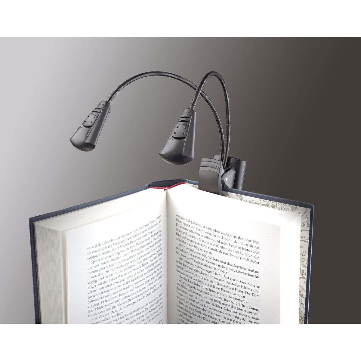 12243 Dual LED FlexLight clipped to the cover of an open book with flexible goosenecks positioned over the pages, K&M