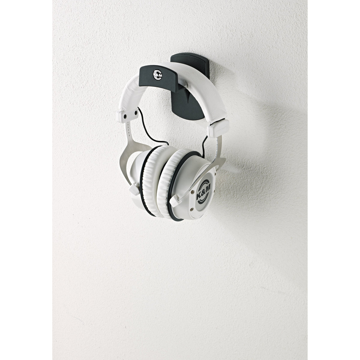 16312 headphone wall holder in use mounted on a white wall with white over-ear headphones hanging from the headband rest, K&M