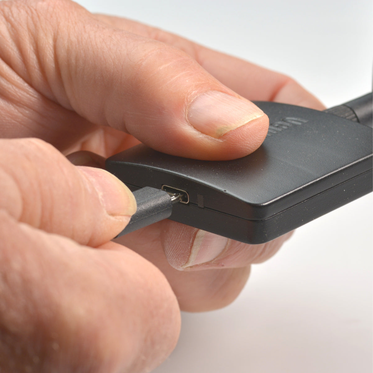 RadioScan 5988 held in hand with USB-C cable aligned to the unit's port, City Theatrical