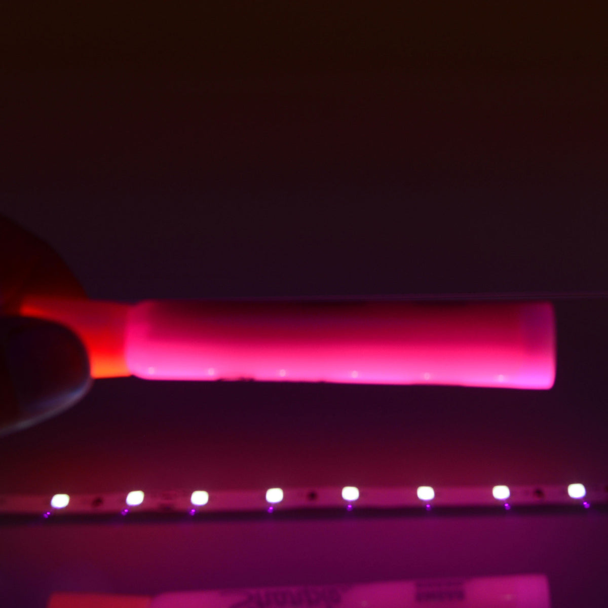QolorFLEX UV LED tape demo with pink highlighter glowing under 395nm blacklight output, City Theatrical