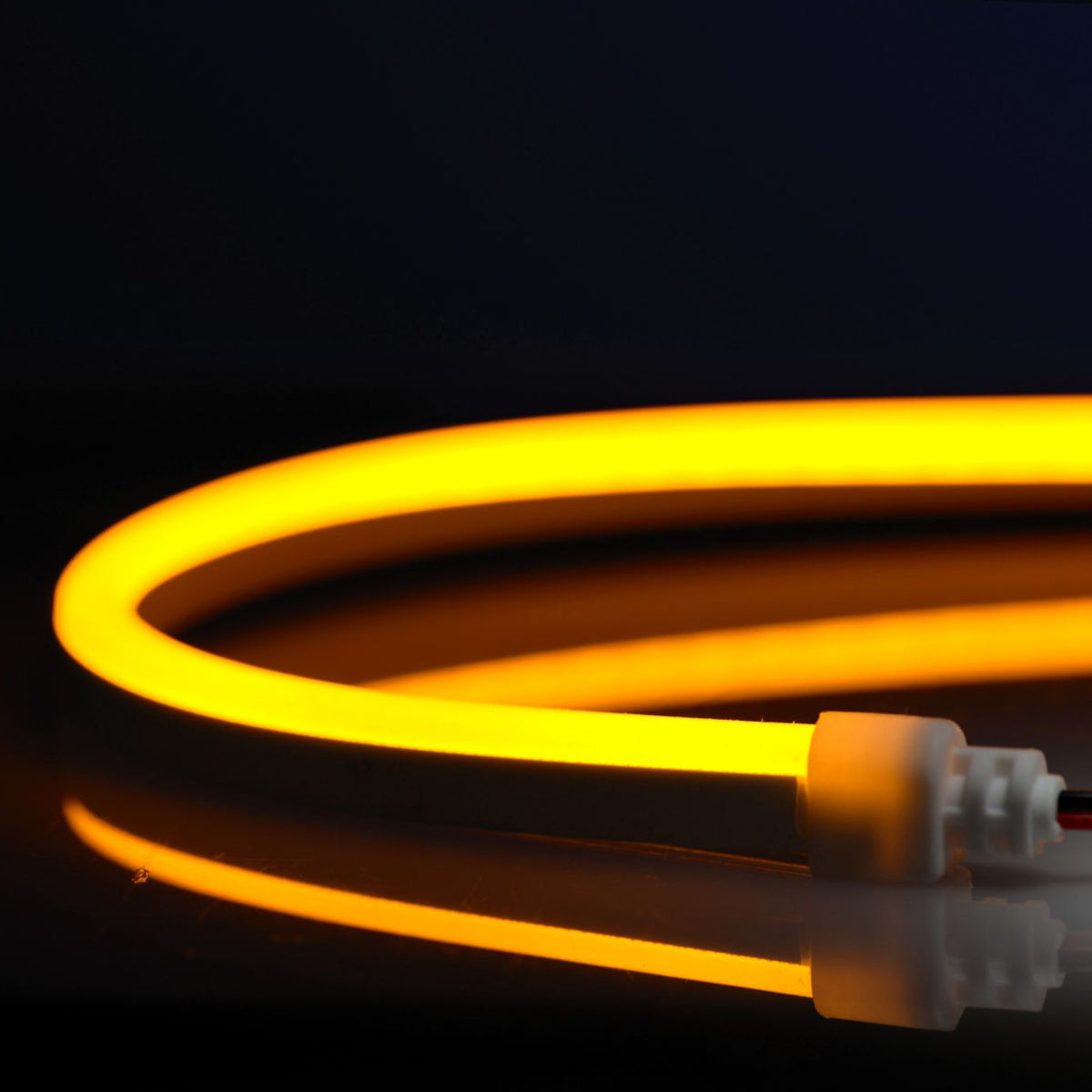 N914-A-10 QolorFLEX NuNeon coiled and illuminated in amber, showing white silicone end cap and lead wires, City Theatrical