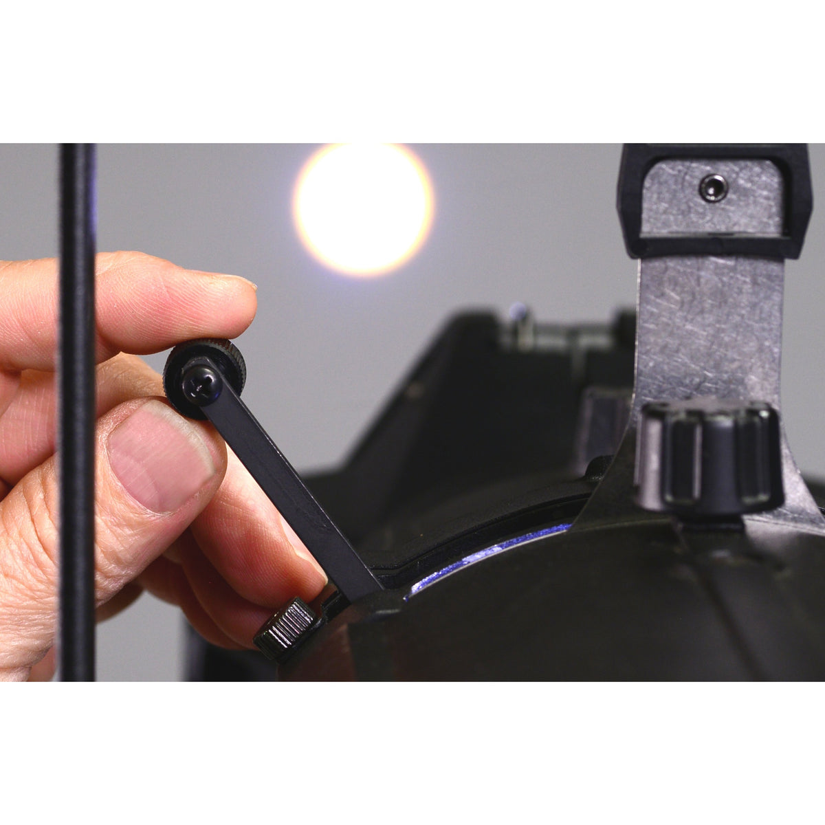 CITTHE 2186 drop-in iris in use, hand adjusting the black control arm on an ellipsoidal fixture's gate slot for precise beam control, City Theatrical