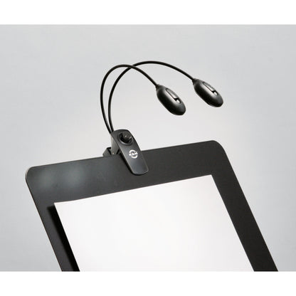 12271 Twin Head Pro music stand light clipped to the top edge of a black music stand desk with gooseneck arms curving over the sheet area, K&M