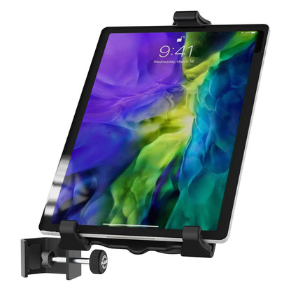Biobased tablet holder in use gripping a tablet showing a lock screen, with table clamp and thumbscrew at lower left, K&M