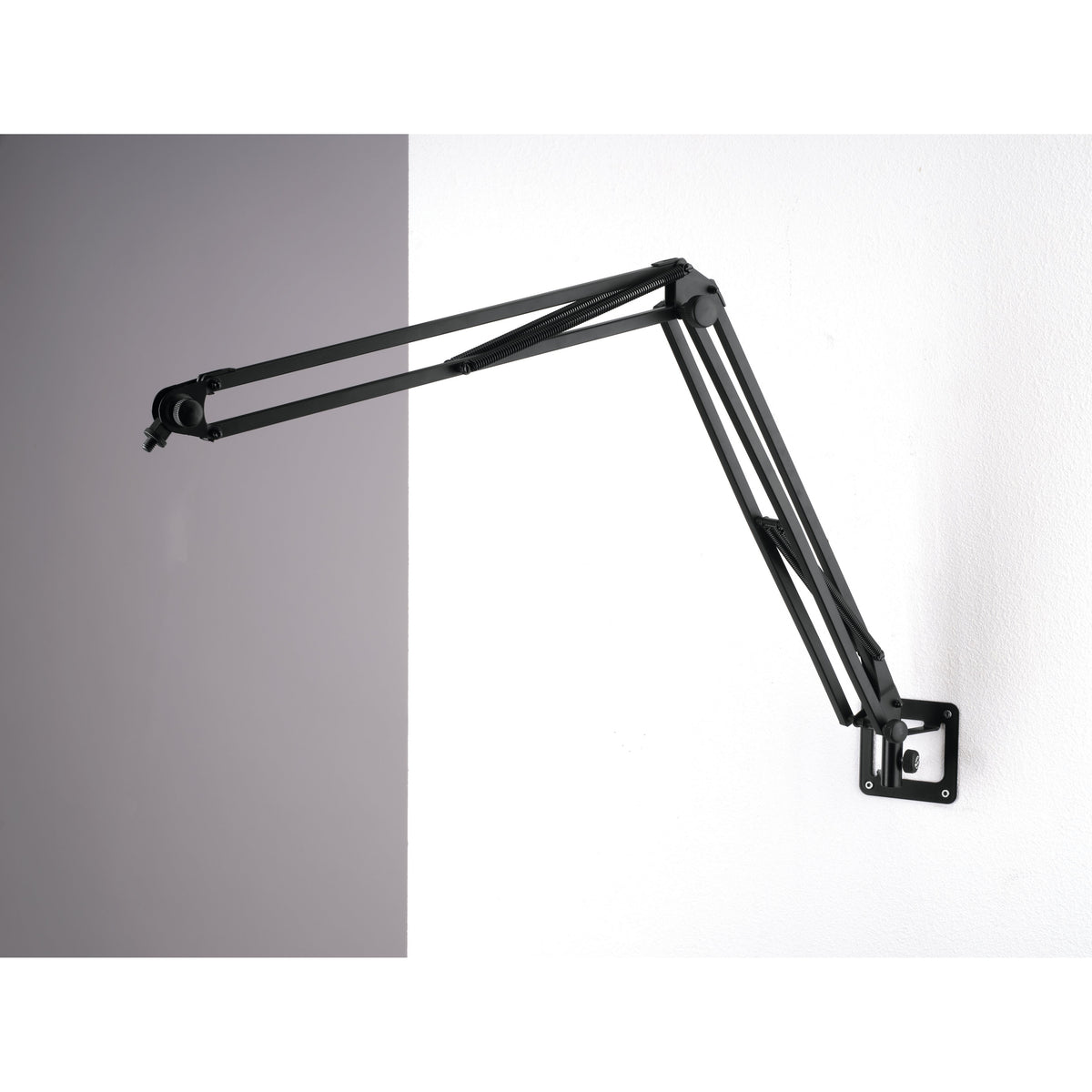 23856 wall mount installed on a white wall holding a black spring-balanced microphone desk arm extended outward, K&M