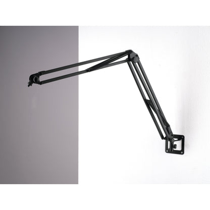 23856 wall mount installed on a white wall holding a black spring-balanced microphone desk arm extended outward, K&M
