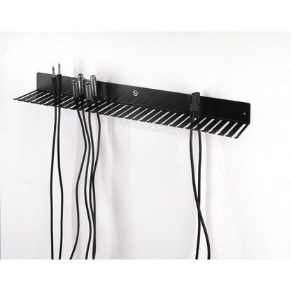49020 cable hanger mounted on white wall in use, holding TRS jack, XLR and IEC mains cables hanging from the slots, K&M