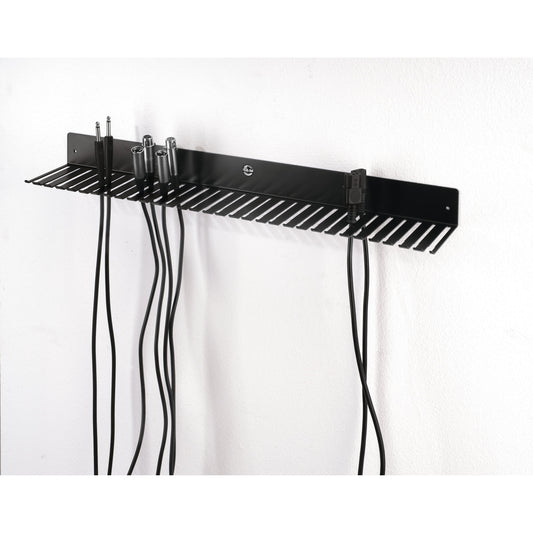 49020 cable hanger mounted on white wall in use, holding TRS jack, XLR and IEC mains cables hanging from the slots, K&M
