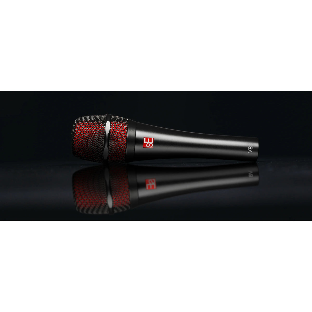 V8 handheld vocal microphone side view lying on a reflective black surface, showing red inner grille mesh, sE logo badge and V8 marking, sE Electronics