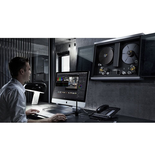 Colorist at a workstation with a wall-mounted Blackmagic Design Cintel film scanner in a suite