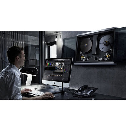 Colorist at a workstation with a wall-mounted Blackmagic Design Cintel film scanner in a suite