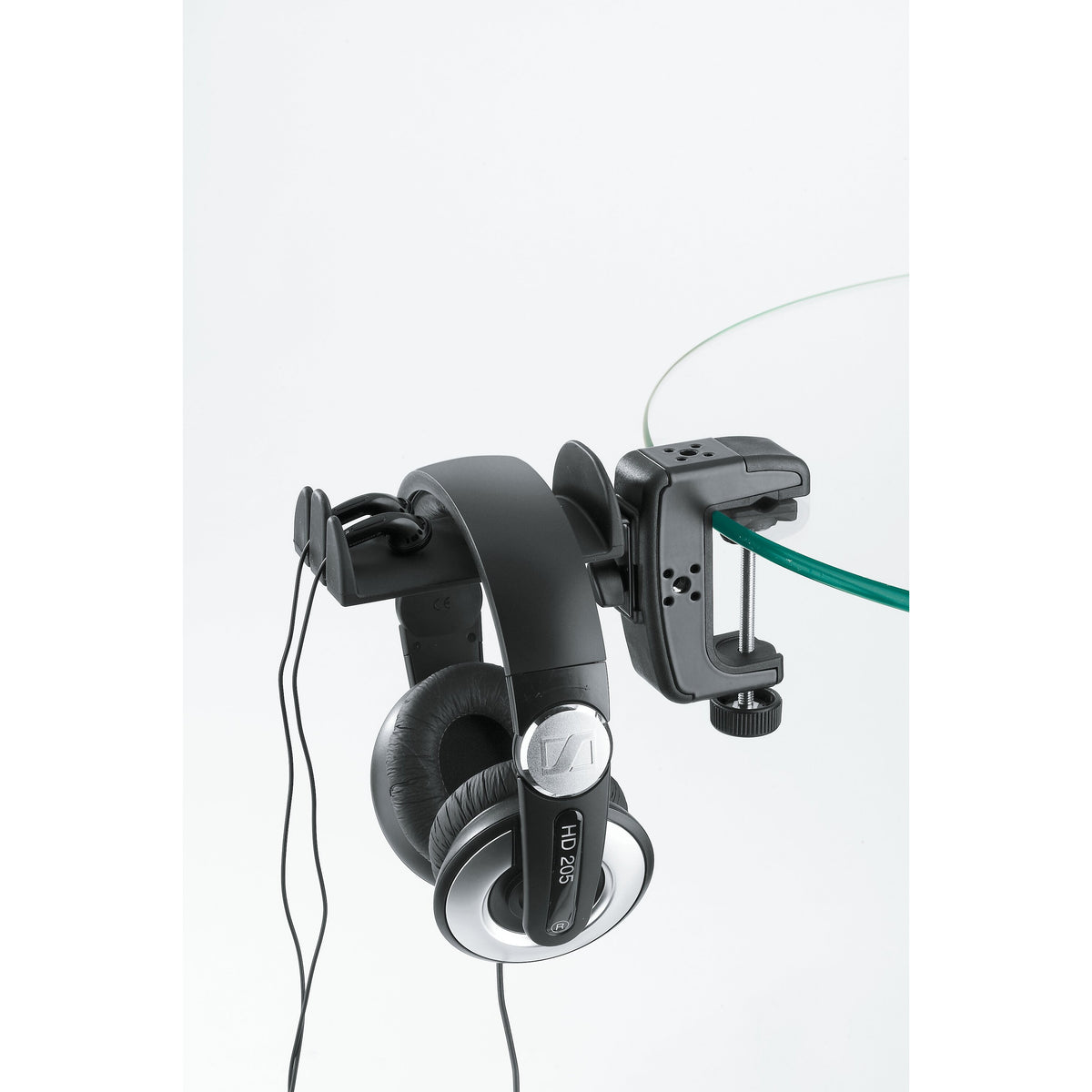 16085 headphone holder clamped to the edge of a glass tabletop, holding Sennheiser HD 205 headphones with cable hooks and thumbscrew visible, K&M