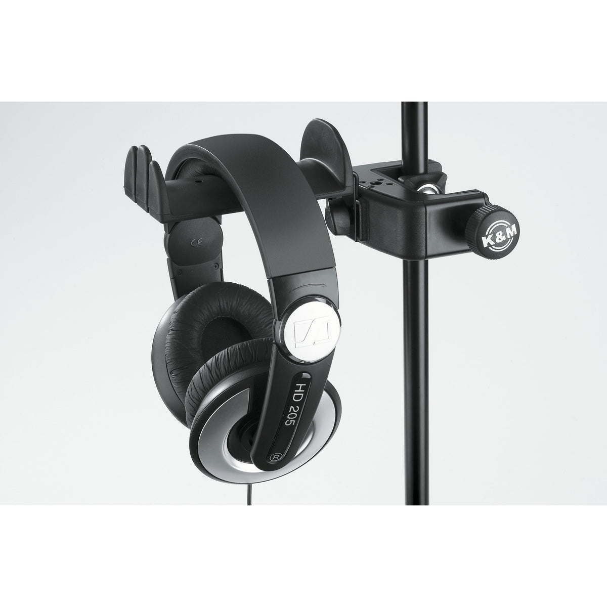 16085 headphone holder close-up mounted on a vertical mic stand tube, K&M-branded clamp knob and HD 205 headphones hanging from the cradle, K&M