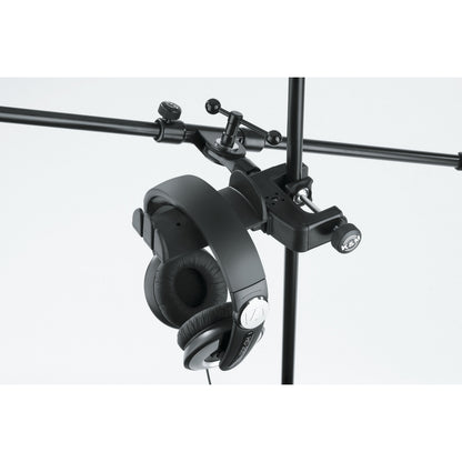 16085 headphone holder clamped to a vertical stand below a horizontal boom arm with clamp knob and headphones hanging, K&M