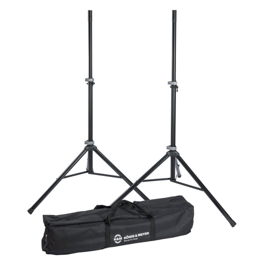 21459 speaker stand pair full set view with two black aluminum tripod stands extended beside the black carrying case printed with the K&M König & Meyer logo, K&M