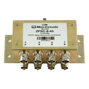 Passive RF splitter/combiner front angled view showing Mini-Circuits ZFSC-8-43 label, COM input connector and numbered BNC ports 1 to 8 on gold metal housing with mounting flanges, Lectrosonics