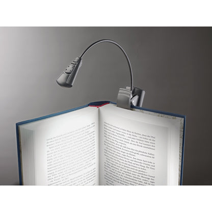 12241 LED FlexLight clipped to the spine of an open book, lit lamp head illuminating the pages, K&M