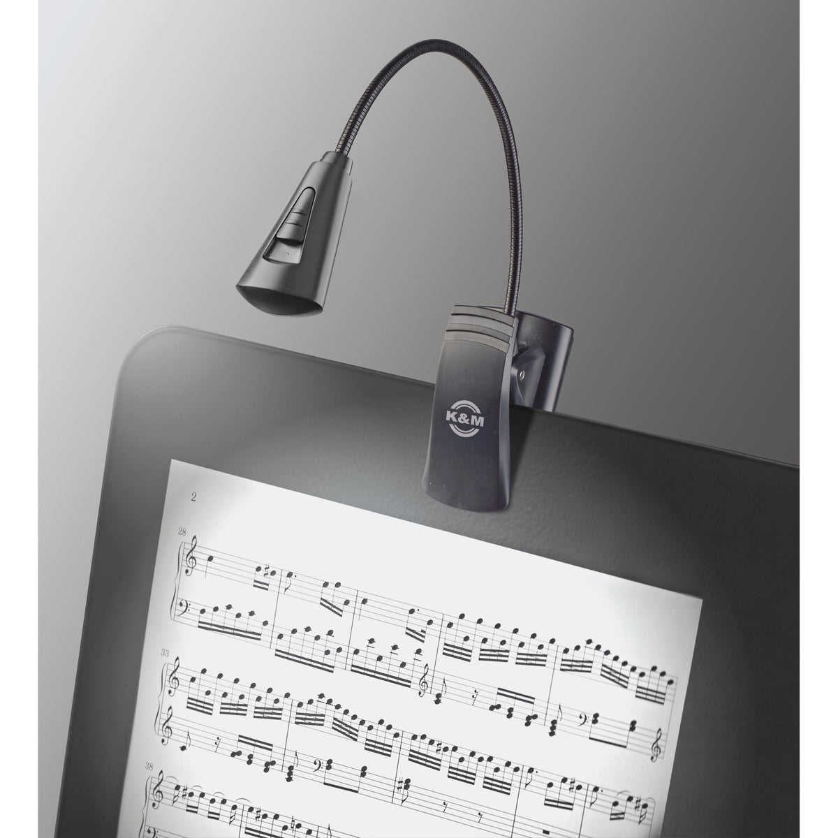 12242 LED flex light in use clipped to a music stand desk with the lamp head and slide switch illuminating sheet music, K&M