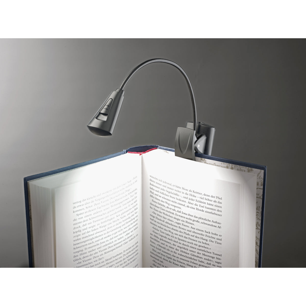 12242 LED flex light clipped to the cover of an open book with the gooseneck arching over to light the pages, K&M