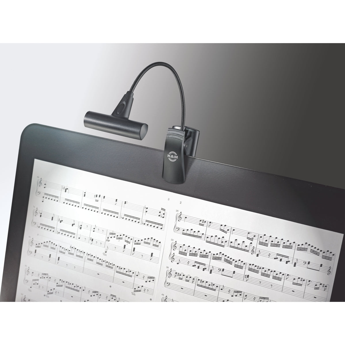 12247 LED FlexLight T-Model in use clipped to a music stand desk, gooseneck holding the light bar over sheet music, K&M