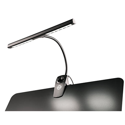 12295 music stand light mounted on a black music desk with LED bar switched on and light pooling across the desk surface, K&M