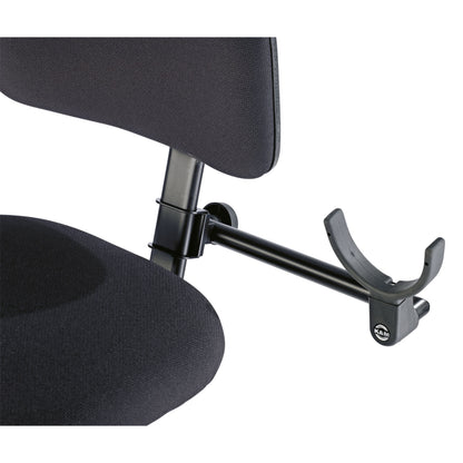 13497 double bass holder in use clamped to the backrest post of a black upholstered bass chair with cradle extended, K&M