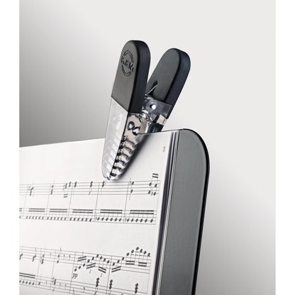 16055 Fix'n Clip close-up detail of black clip with embossed K&M logo and clear ribbed jaw holding sheet music pages, K&M