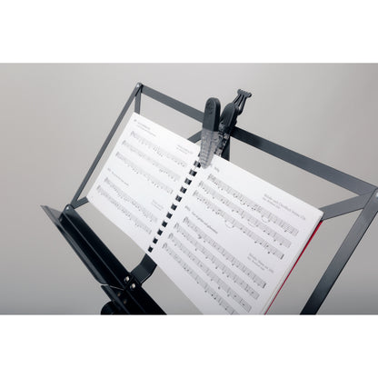 16055 Fix'n Clip in use on a music stand, securing the spiral binding of an open songbook with the clip's magnetic back, K&M