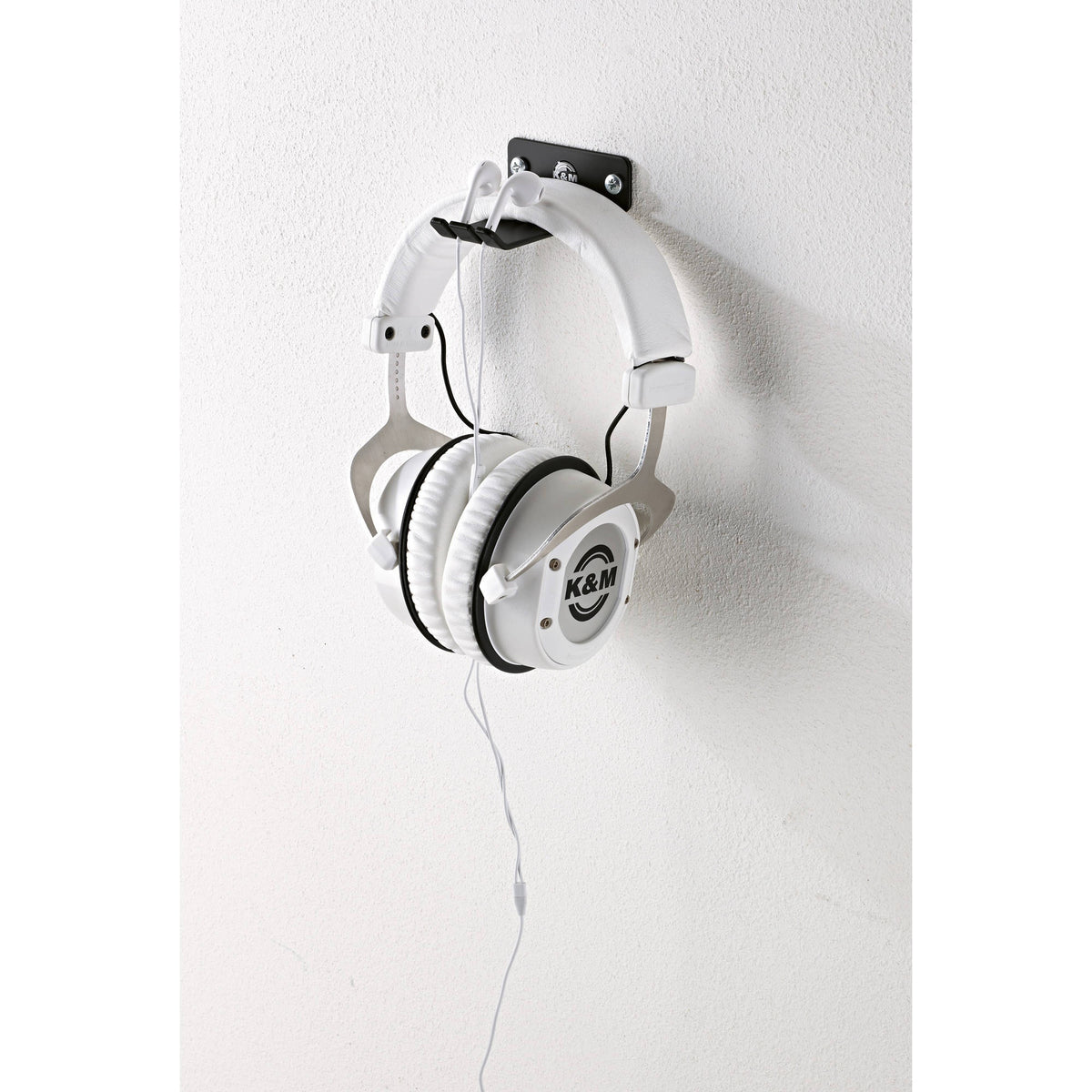 KM 16311.000.55 headphone wall holder in use, white over-ear headphones hung on the black bracket with cable draped down, K&M