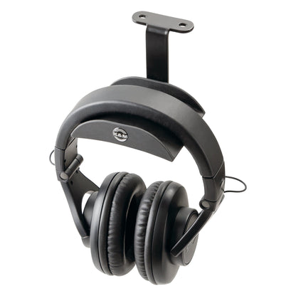 16330 under-table headphone holder in use with over-ear studio headphones resting on the rubber support, mounting plate visible above, K&M