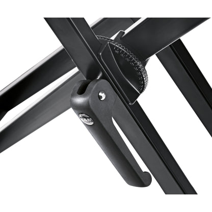 18997 keyboard stand close-up of the center pivot with the toothed height-adjustment wheel and black locking lever bearing the K&M logo, K&M