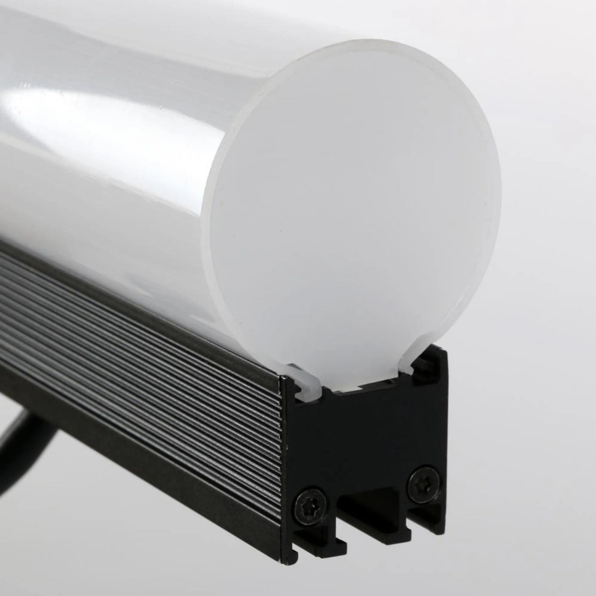 VDO Sceptron 1000mm tube diffuser end detail showing frosted cylindrical lens seated on black finned aluminum fixture body with Torx mounting screws, Martin Lighting